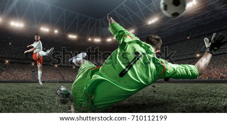Soccer player scoring a goal. Goalkeeper tries to hit the ball. Players wears un-brand uniform.
