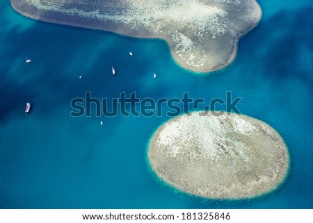Aerial view of a circle coral reef in the ocean with boats around in blue water off the coast of Oahu Hawaii  from a helicopter