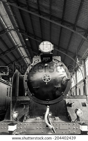Low-angle front view of an old steam locomotive parked inside an old and unused train station in Madrid, Spain. Retro toned.