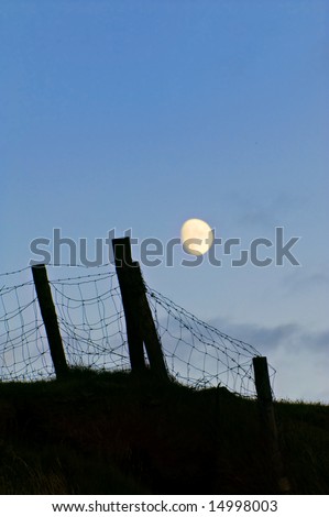 boundry fence posts and wire silhoutte in moonlight