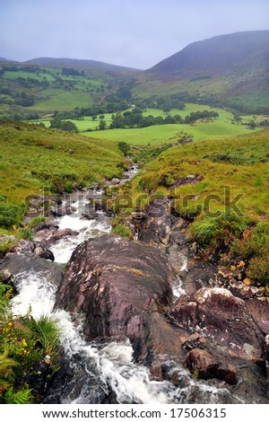 Gleninchaquin Park, Co.Kerry, Ireland showing rocks and stream  with mountains in background