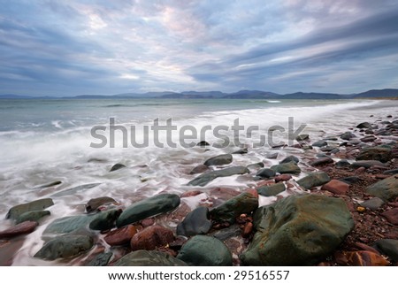 incoming tide washes over rocks and sand at Rossbeigh Strand in Dingle Bay, Co.Kerry, Republic Of Ireland