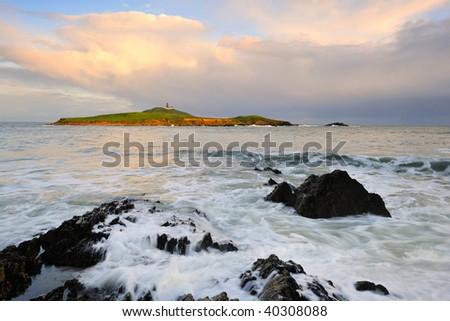 swirling waters as waves break on foreground of Ballycotton Bay, Co.Cork, Ireland,with Ballycotton Lighthouse in background
