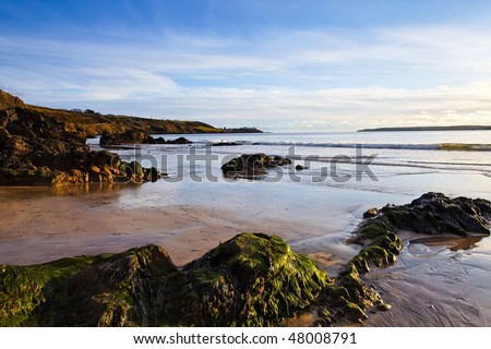 bright sunlight illuminates sand and rocks at White Strand, Co.Cork, Ireland