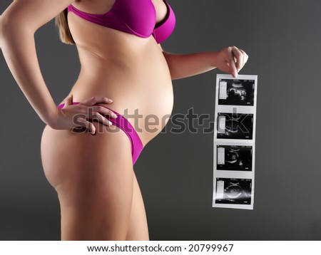 A shot of a pregnant woman carrying her child's ultrasound picture
