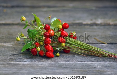 Bouquet of wild strawberry with berries on wooden table