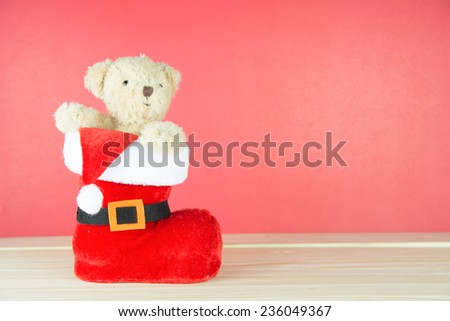 Santa boots and bear on wood on red background, concept christmas