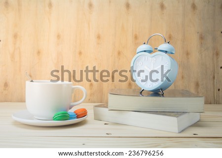 blue heart clock with bell and and a book and a cup of coffee with macaroons on wood background,vintage tone