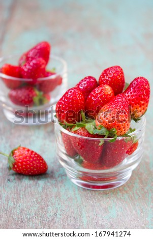 Small glass with succulent juicy fresh ripe red strawberries on wooden textured table top