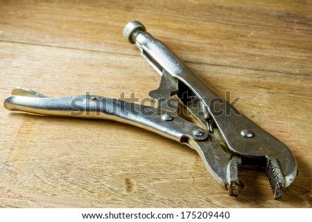 locking pliers on a wooden panel with space for text