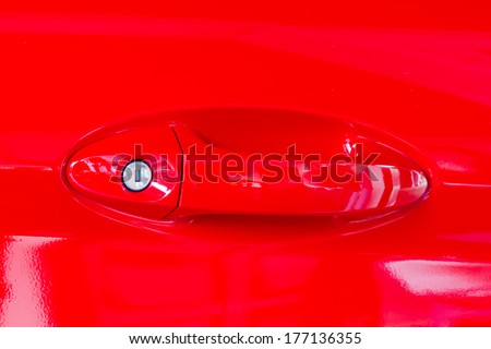 A glossy red painted car door with door edge and a handle