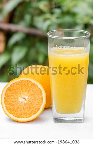 Glass of freshly pressed orange juice with sliced orange  on wooden table