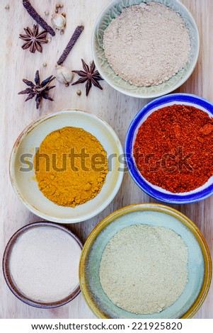 Assorted hot spicy powders in ceramic bowls on wooden