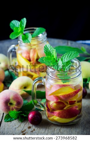 Jar delicious refreshing drink of peach fruits and plum  with mint on wooden, infused water