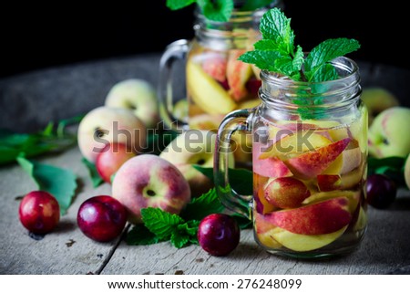 Jar delicious refreshing drink of peach fruits and plum  with mint on wooden, infused water