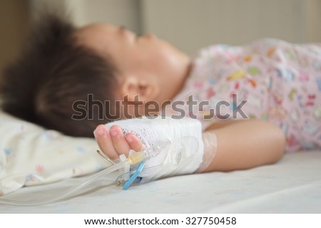 Illness little asian (thai) baby asleep on a sickbed in hospital, saline intravenous (IV) on hand