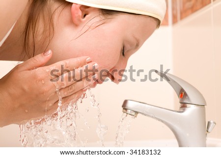 Woman cleaning face in bathroom