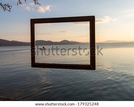 A fisherman captured in a frame after  tending his nets on Lago Trasimeno, Perugia, Italy at dusk.  The lake is a shallow muddy lake abundant with fish