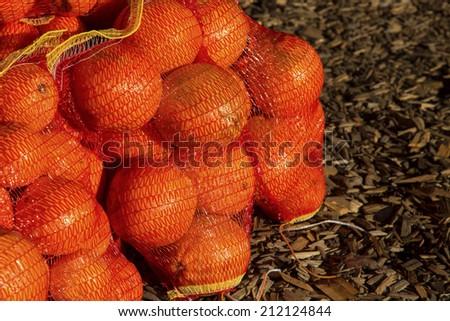 Bags of seasonal oranges on wood chip floor at farmers market