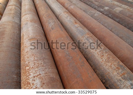 A group of large cast iron pipes lie in parallel after being used in a river dredging operation.