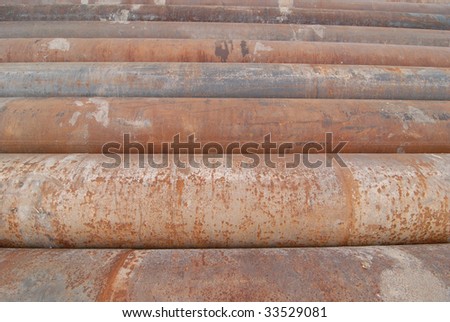 A group of large cast iron pipes lie in parallel after being used in a river dredging operation.