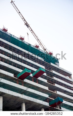Construction work being done on a building using a crane and safety nets. The recent growth of India has been closely tied with numerous infrastructure projects