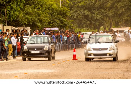 Delhi, India; 14th Mar 2015 - Crowd of people watching a couple of cars drag racing on a dusty road in Delhi. This was one of the events at Delhi College of engineering