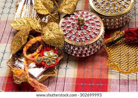 Collection of indian handicraft items with rakhi, jewelled boxes and golden leaves