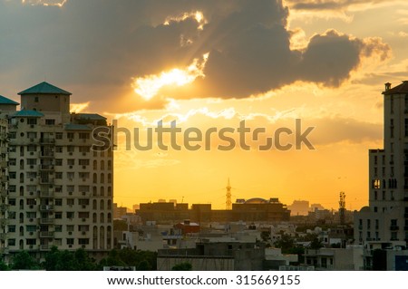 Gurgaon apartments at sunset with light rays passing through the clouds and giving a golden glow