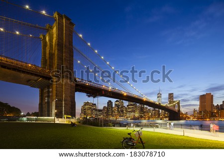 The Brooklyn Bridge in front of the Manhattan skyline in New York City at night.