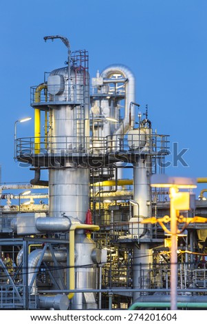 Detail of distillation towers in a chemical plant and refinery with night blue sky.
