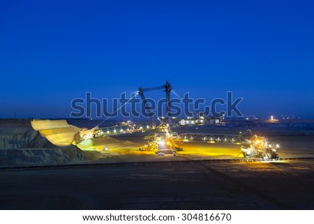 A giant Bucket Wheel Excavator at work in a lignite pit mine at night with some motion blur