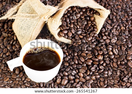 Coffee bag on the pile of coffee beans with cup of coffee