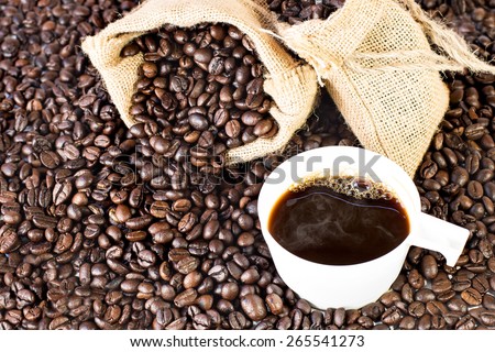 Coffee bag on the pile of coffee beans with cup of coffee