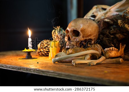 Skull and pile of bone with light candle, Still Life style