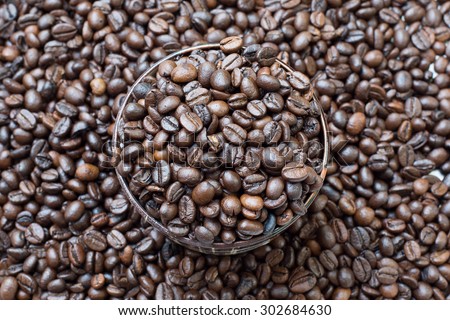 Coffee beans roasted in cup, on pile of coffee beans, Select focus