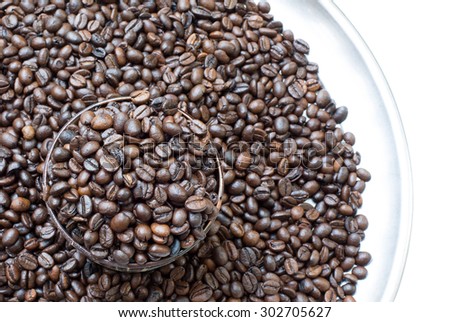 Coffee beans roasted in cup, on pile of coffee beans, Select focus