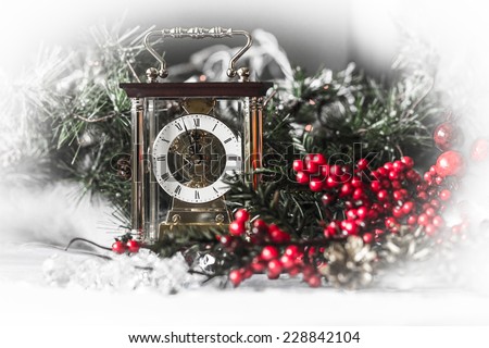New Year composition with the Carriage clocks that show midnight, red berries and cones in the foreground