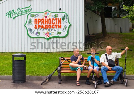Russia, Moscow, July 8, 2014 - Park of Culture and Rest Gorky. Father and sons sit down to rest on a bench with their scooters.