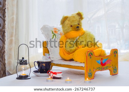 Bear - a toy is in the crib, and measures the temperature of the thermometer near the Bears candles, jar of jam,  a cup of tea.