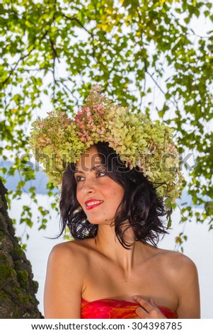 young Russian woman on her head a wreath of flowers hydrangeas, a woman relaxed, reclining on a tree trunk, happy, Russian traditions and folk life, lifestyle and clothing, intimate nature,