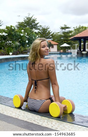 The girl is engaged aqua aerobics with dumbbells