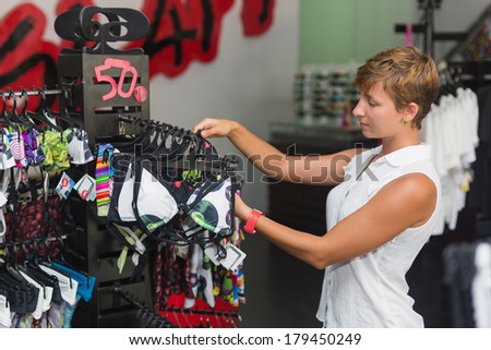 woman buys in the store swimsuit. beautiful young woman chooses to buy clothes in shop, bikini