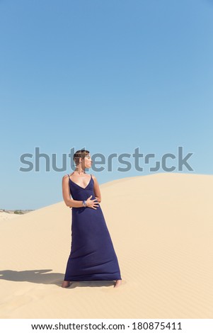 beautiful adult sensuality woman in dress on blue sky and sand background