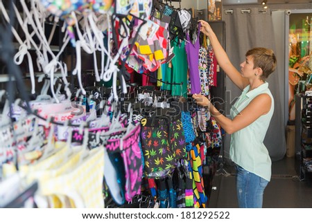 beautiful smiling woman shopping in retail store,woman buys in the store swimsuit, bikini
