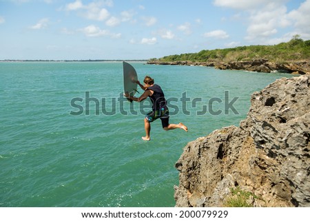 surfer jumps off a cliff into the ocean