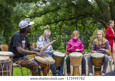 Oblegorek, Poland - July 31, 2011: Black musician from Africa demostrates how to play the drums to local children at free public workshops in Oblegorek on July 31, 2011.