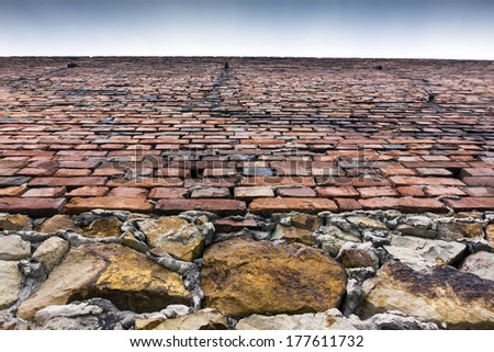 Stone and brick wall of an old building seen under angle from the ground