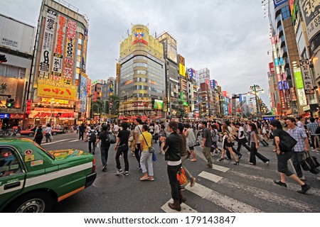 TOKYO - JUNE 26, 2010: Busy streets in Shinjuku district, with crowds of people, green Tokyo taxi and neons in background on 26 June 2010.