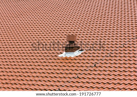 small metal red chimney on the roof composed of red tiles